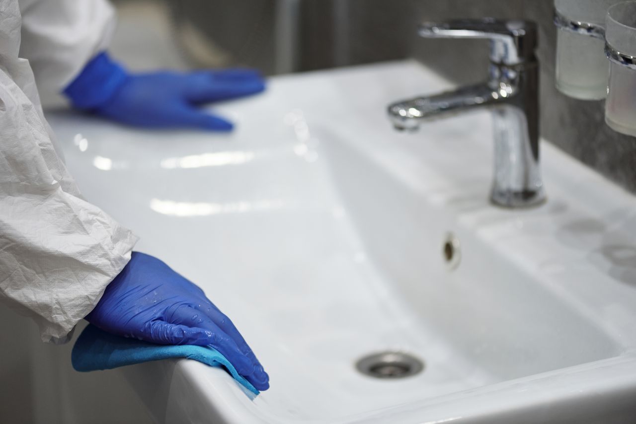 services-03 Close-up of a gloved professional cleaning a sink for sanitation.